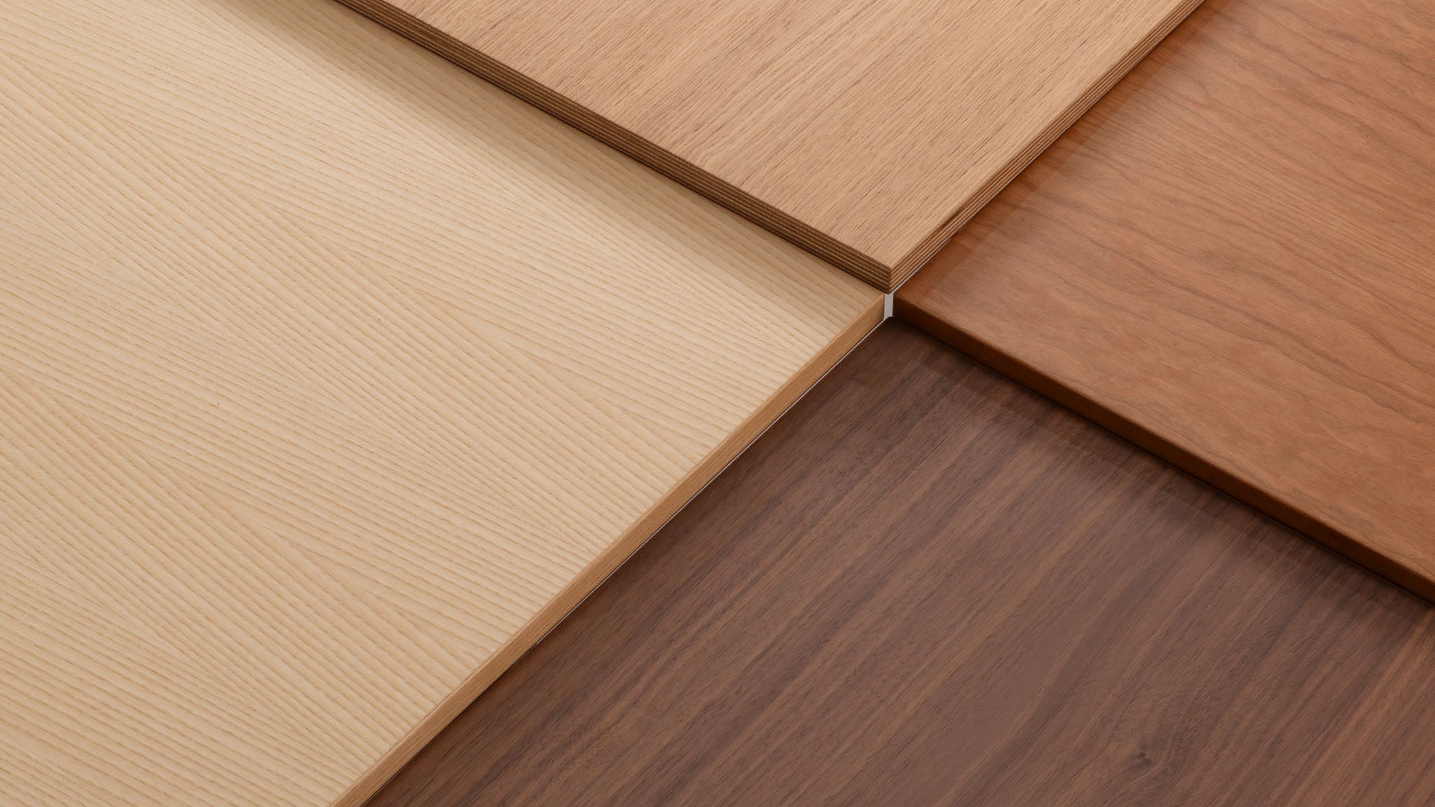 Four rectangular wooden panels in light and dark shades intersect at right angles, showcasing different wood grain patterns and colors, arranged in a neat geometric layout.