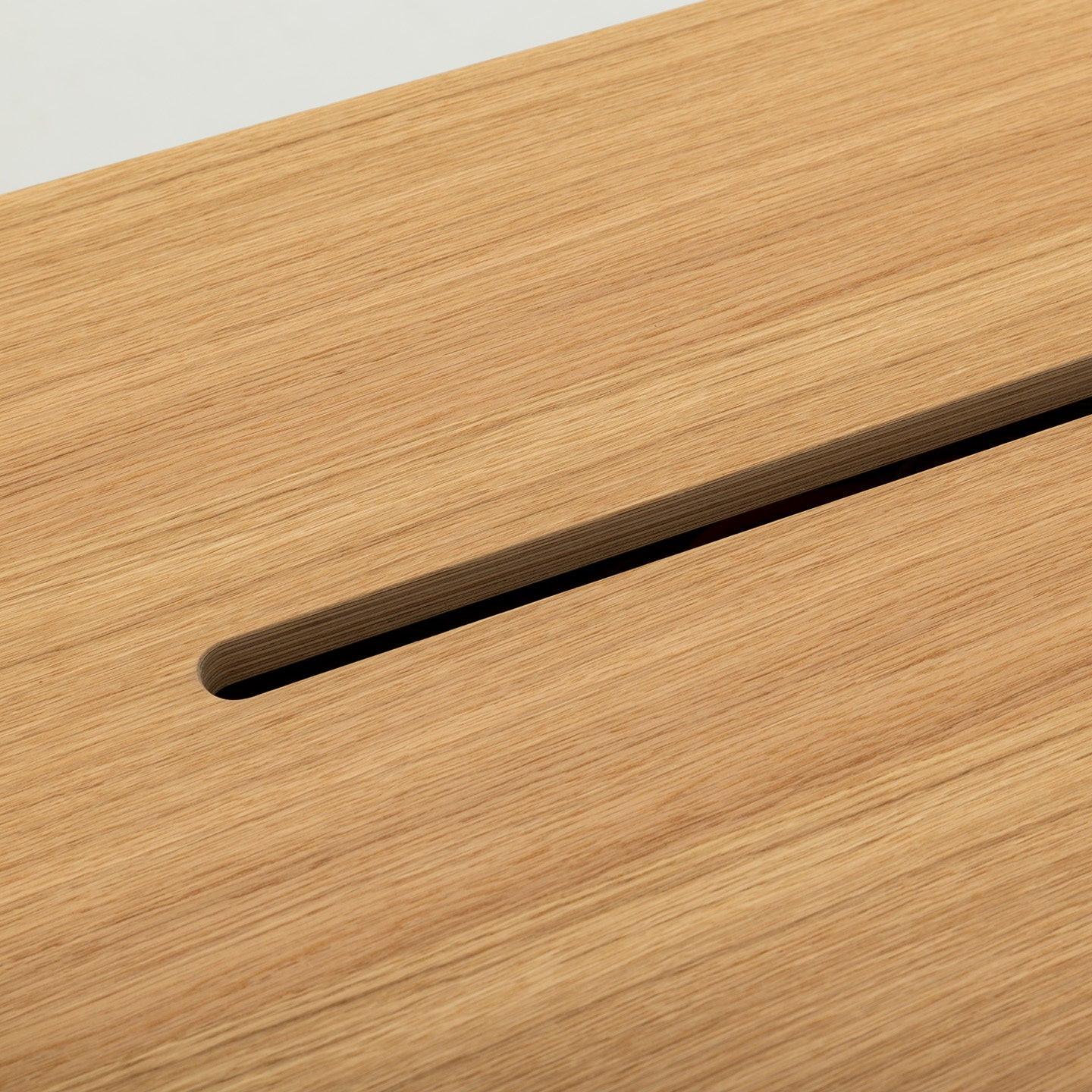 Nahaufnahme der glatten, hellen Holzoberfläche des MAX von CUBE Products & Furniture mit einem einzigen diagonalen rechteckigen Schlitz - perfekt für XL-Setups oder mehrere Monitore in großen Arbeitsbereichen. Die feine Holzmaserung bildet einen schönen Kontrast zu dem neutralen Hintergrund.