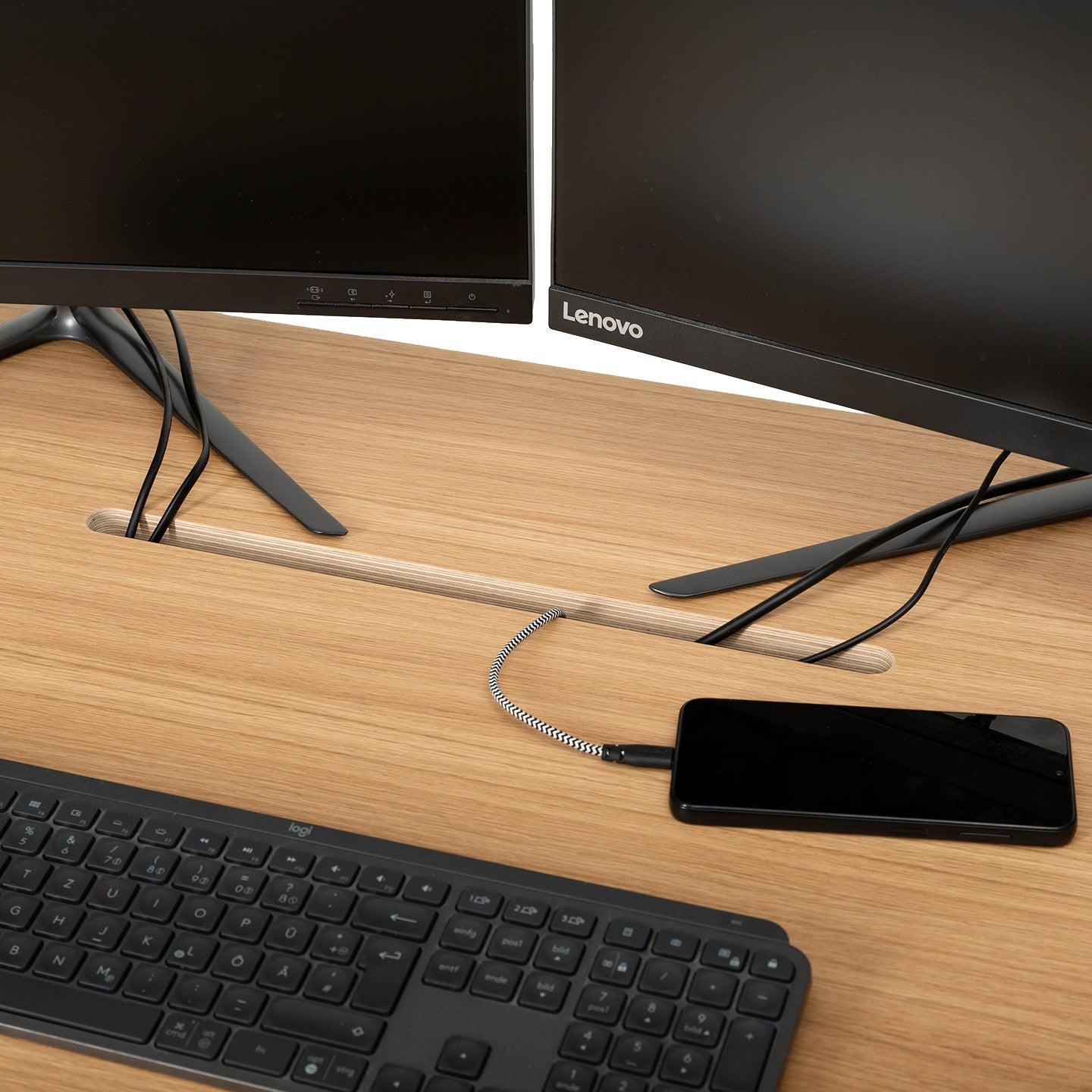 Ein aufgeräumter MAX-Schreibtisch aus Holz von CUBE Products & Furniture bietet Platz für eine schwarze Tastatur, ein verkabeltes Smartphone und zwei Lenovo-Monitore auf Ständern. Die Kabel laufen ordentlich durch einen Schlitz in diesem organisierten XL-Setup.