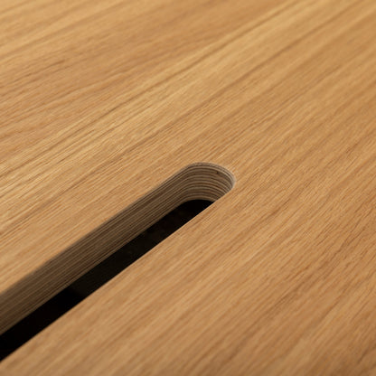Close-up of the smooth, light surface of Kabeldurchlass - Oblong gefräst, featuring a rounded rectangular slot (Langloch) that displays layered wood edges and a dark space beneath.